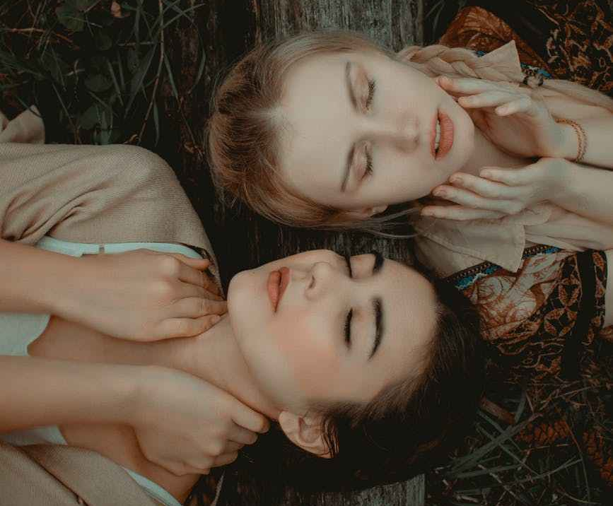 photo of two women lying on grass