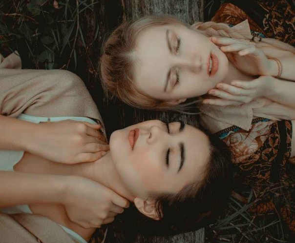 photo of two women lying on grass
