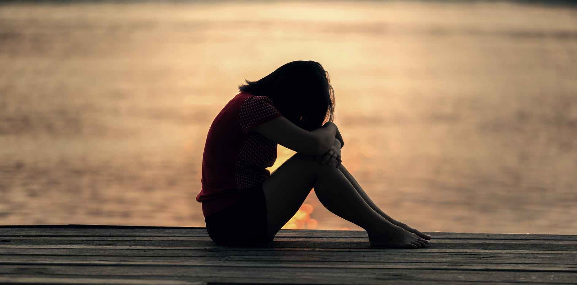 woman looking at sea while sitting on beach